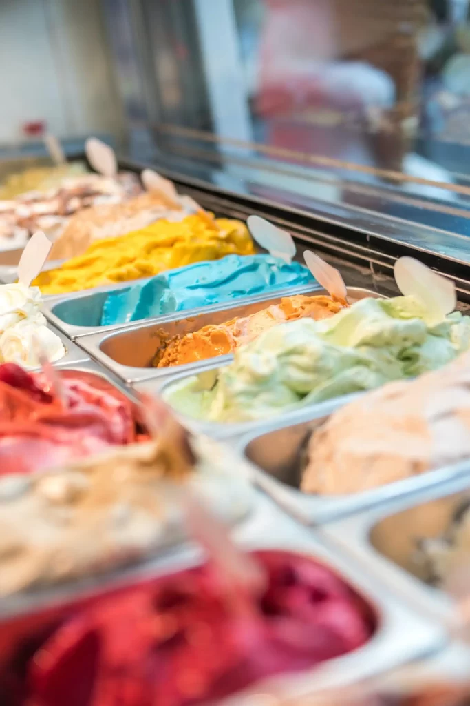 A colorful assortment of ice cream flavors in a display case, showcasing vibrant options like blue, yellow, red, and green.