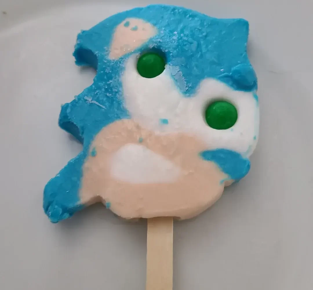 A partially melted Sonic popsicle with gumball eyes on a plate.